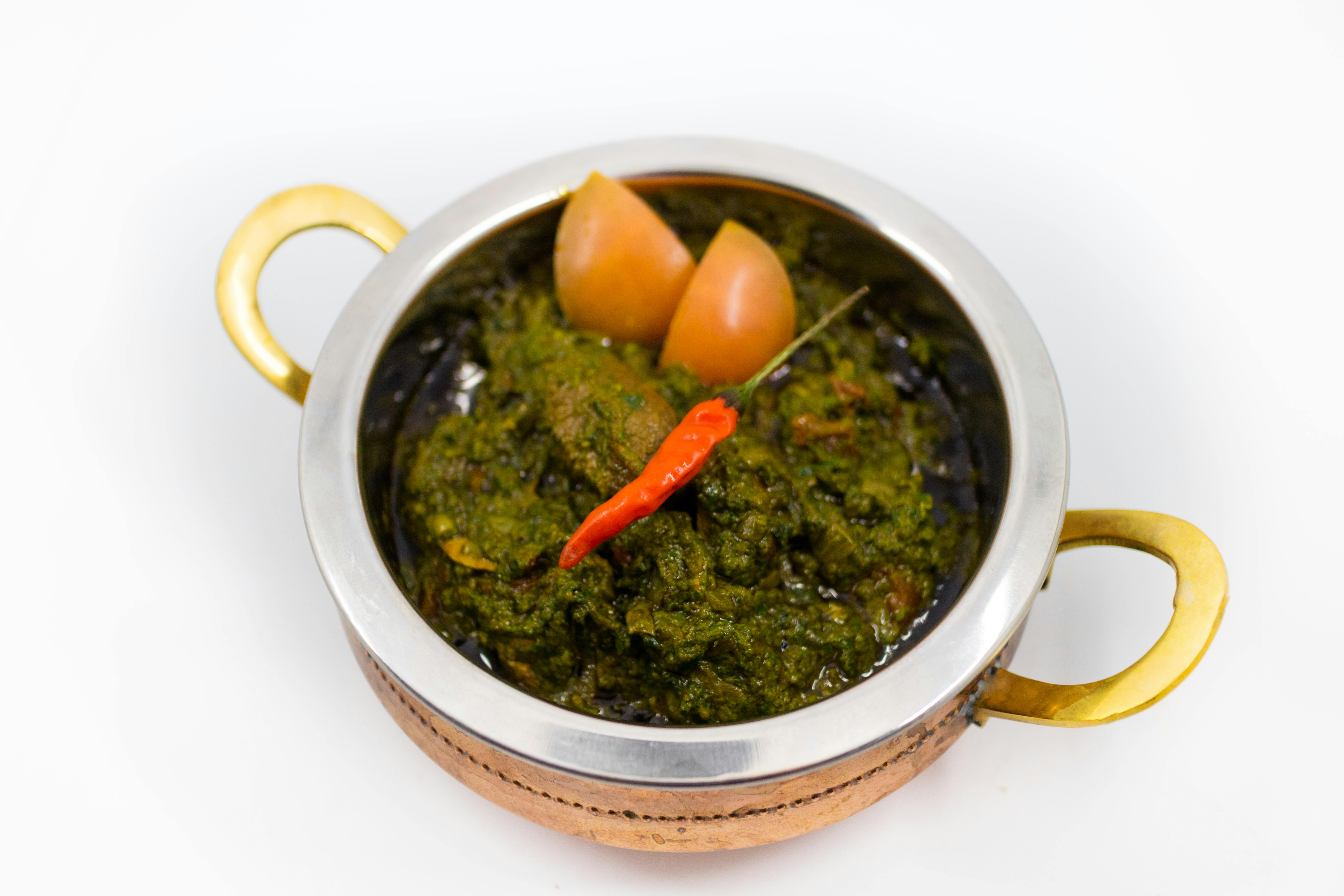Bowl filled with creamy saag paneer featuring golden cubes of paneer cheese nestled in vibrant green spinach sauce, garnished with a sprinkle of spices, set on a rustic wooden table with warm, inviting lighting